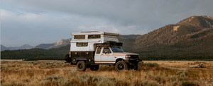 Truck camper setup in a scenic mountain location, showcasing overlanding gear and off-road vehicle amidst the mountains. 